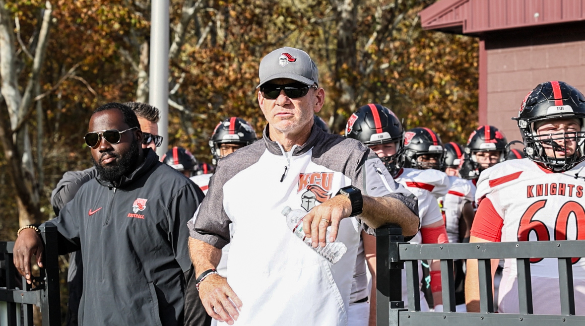 Coach Jason Aubry leading the KCU football team onto the field